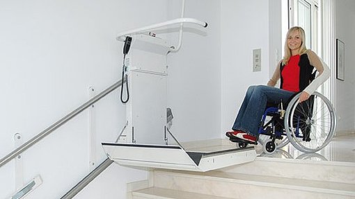 Eine junge Dame benutzt mit ihrem Rollstuhl den Plattformtreppenlift DELTA